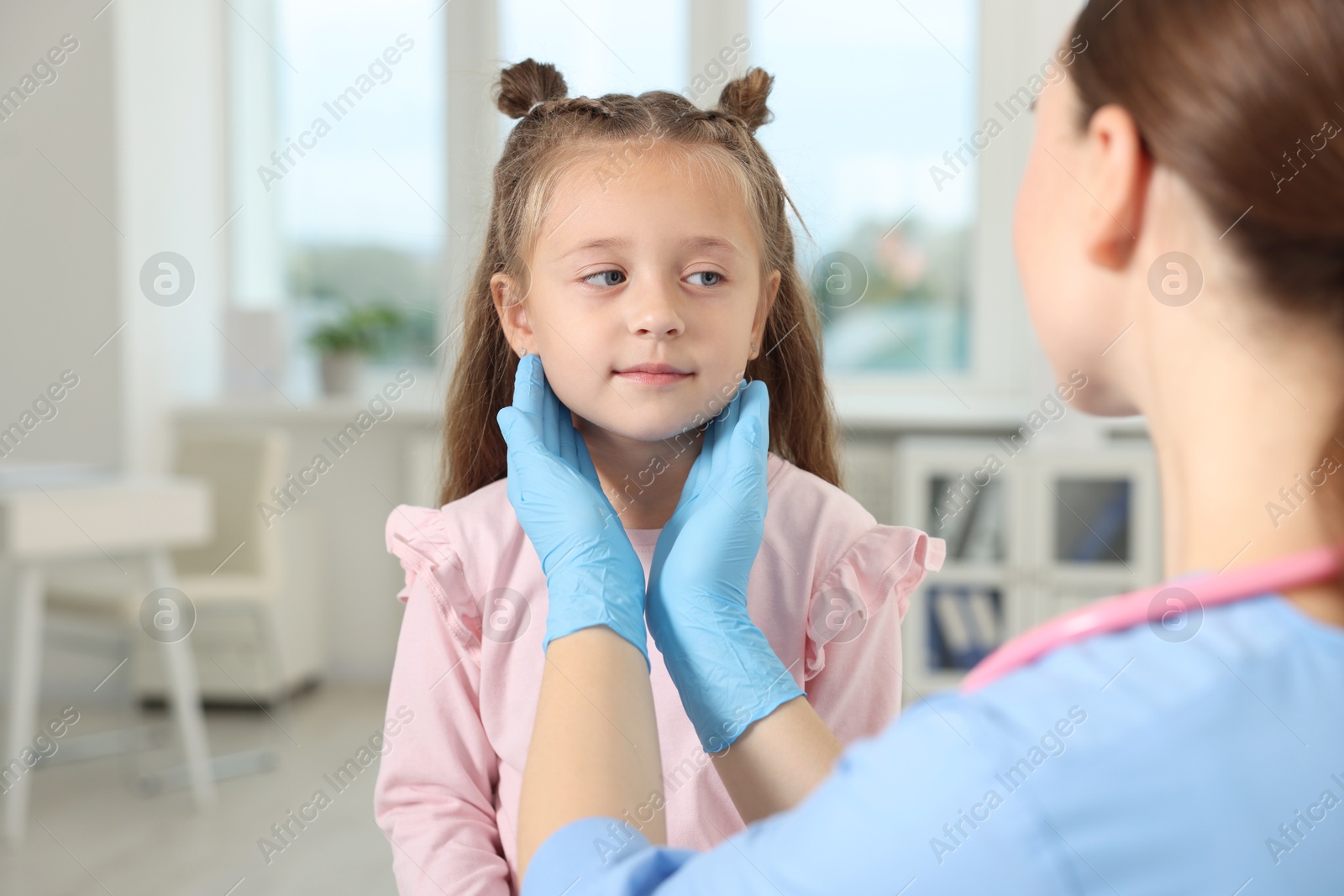 Photo of Doctor examining girl's throat in clinic during appointment