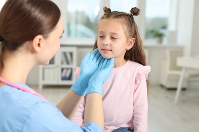 Photo of Doctor examining girl's throat in clinic during appointment