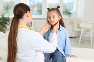 Photo of Doctor examining girl's throat in clinic during appointment