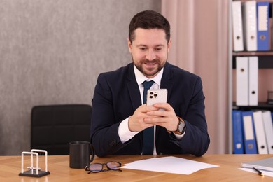 Photo of Banker using smartphone at wooden table in office