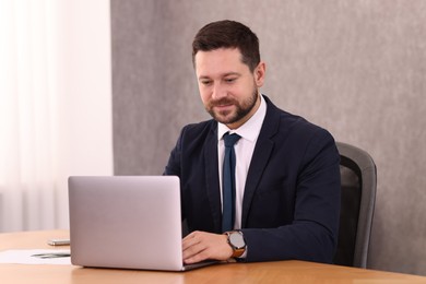 Photo of Banker working with laptop at wooden table in office