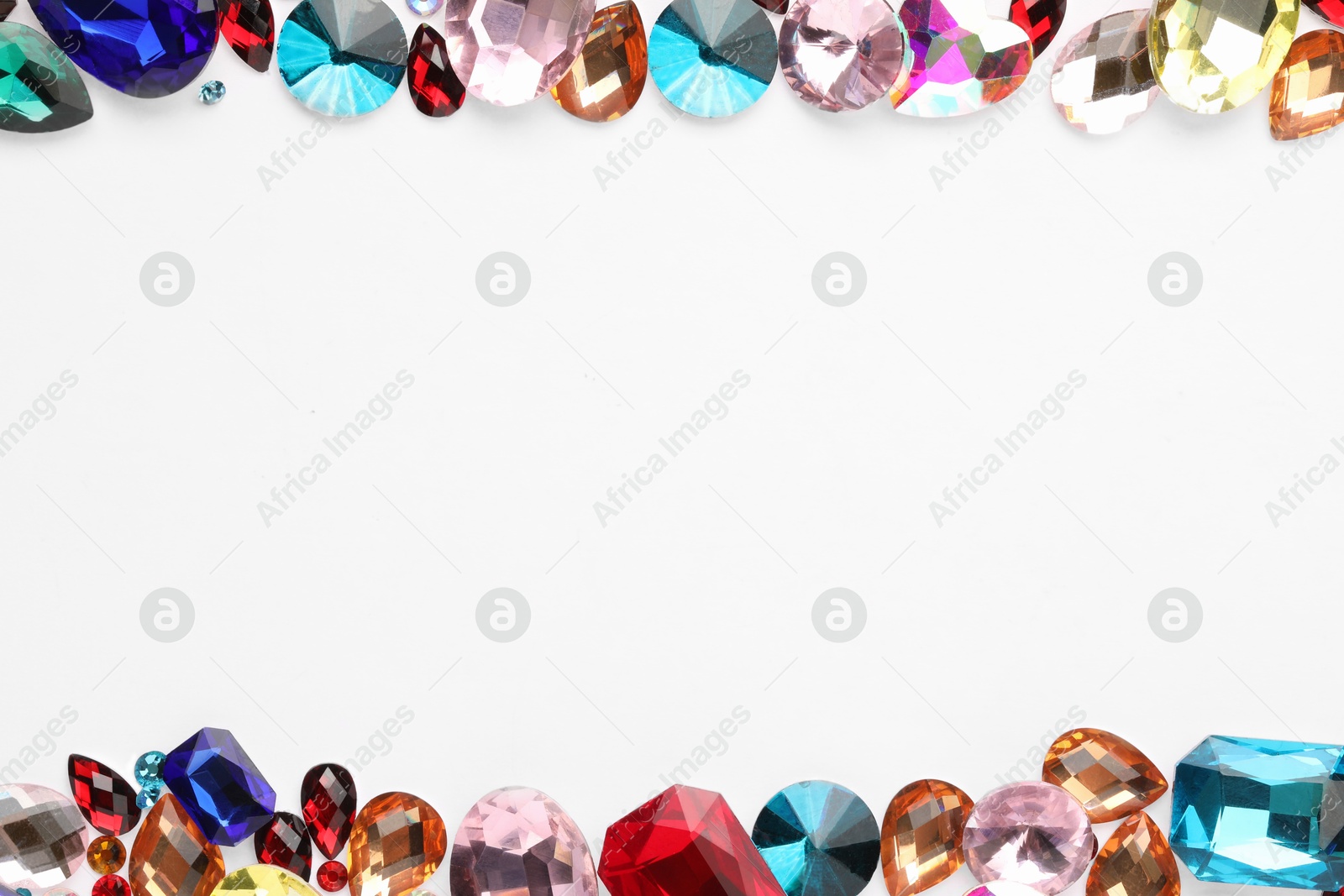 Photo of Frame of different shiny gemstones on white background, flat lay. Space for text