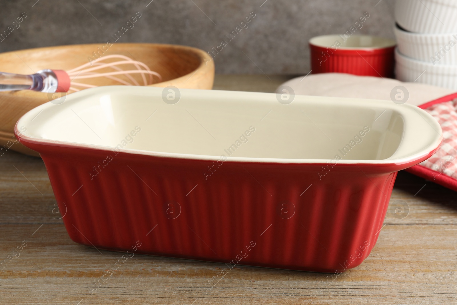 Photo of Ceramic casseroles and other cooking utensils on wooden table, closeup