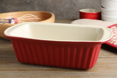 Photo of Ceramic casseroles and other cooking utensils on wooden table, closeup