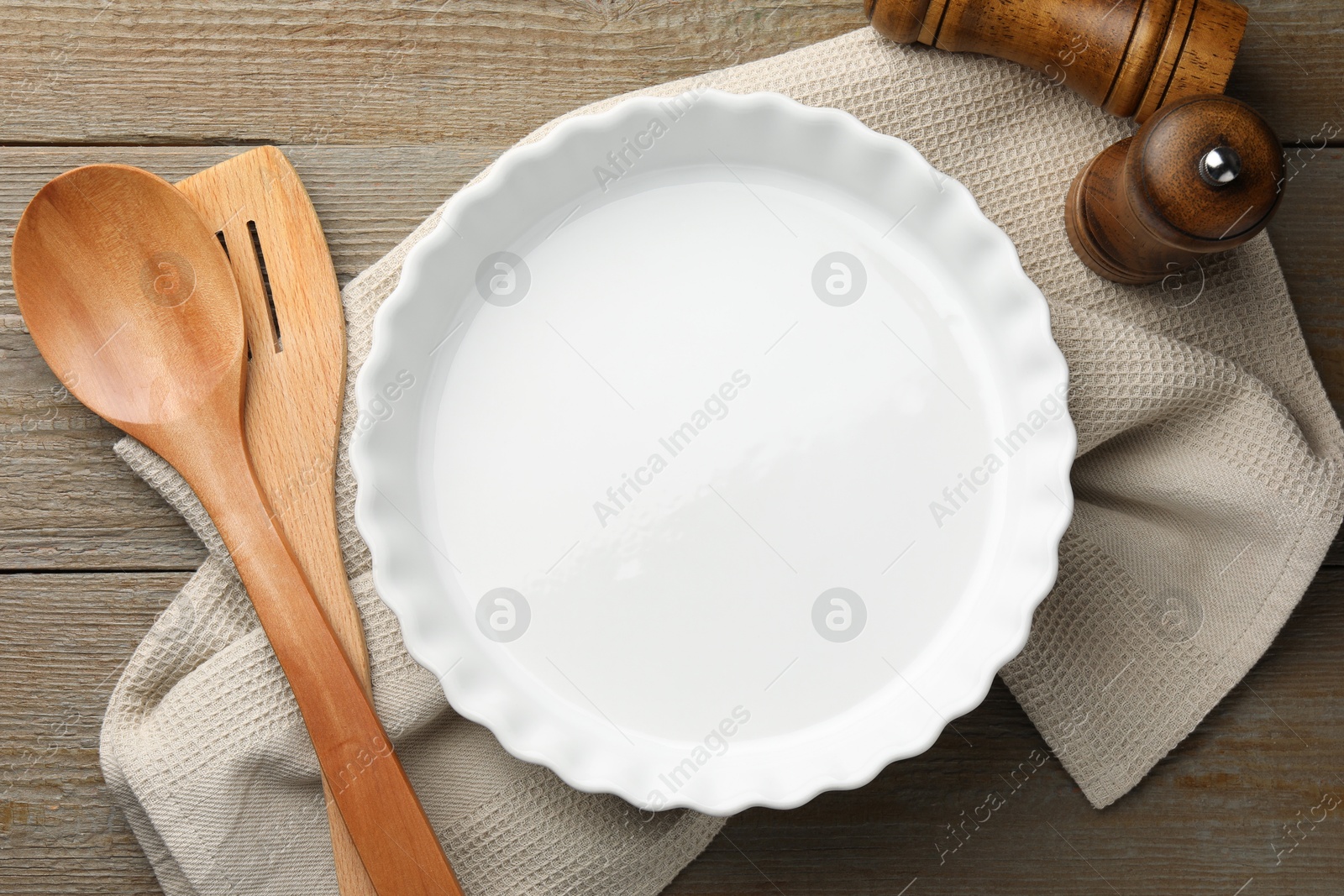 Photo of Ceramic casserole and other cooking utensils on wooden table, flat lay