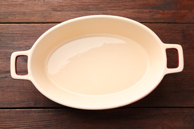 Photo of One ceramic casserole on wooden table, top view