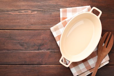 Photo of Ceramic casserole and slotted turner on wooden table, top view. Space for text