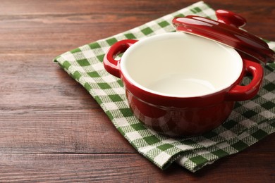 Photo of Ceramic casserole and lid on wooden table, closeup. Space for text