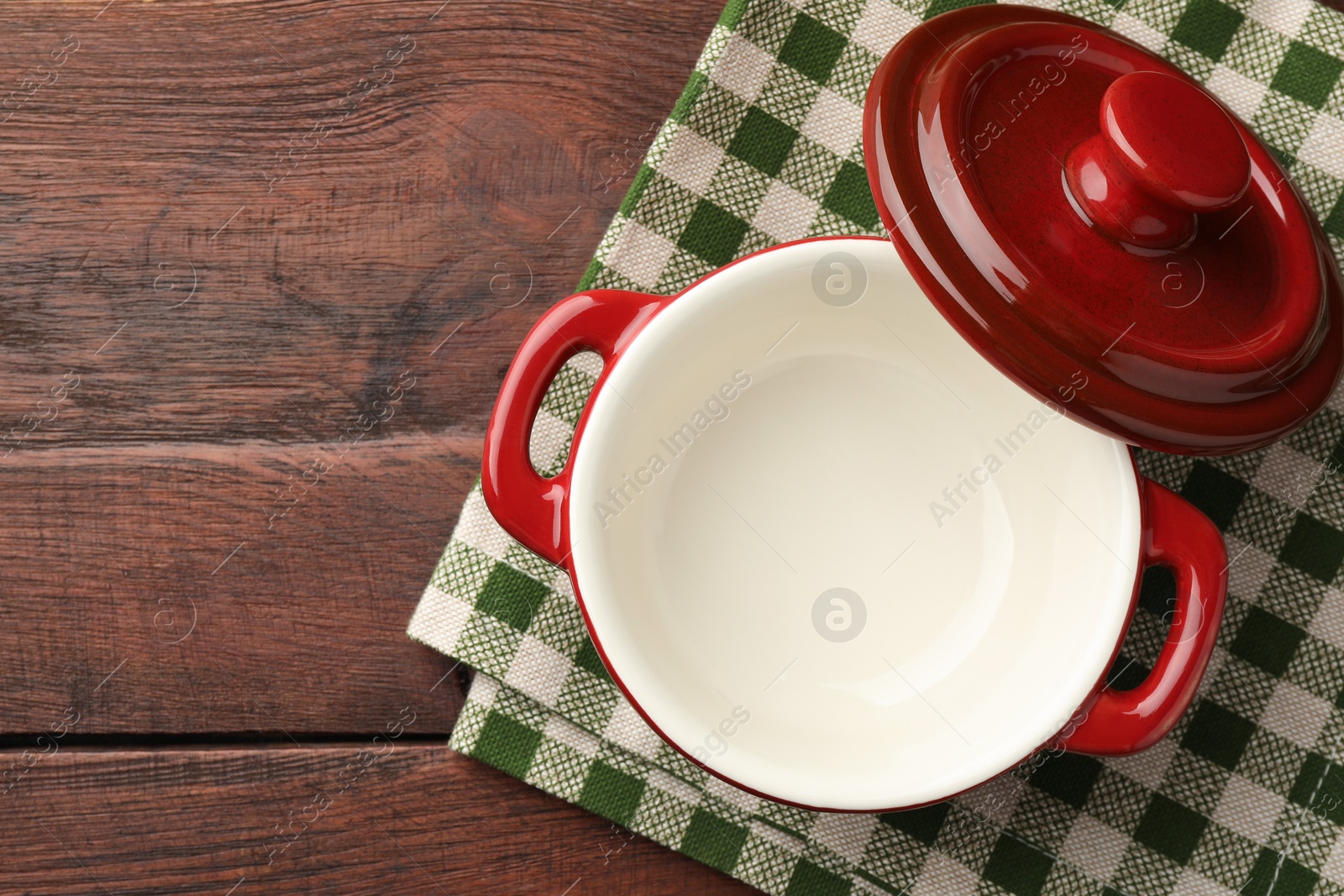 Photo of Ceramic casserole and lid on wooden table, top view. Space for text