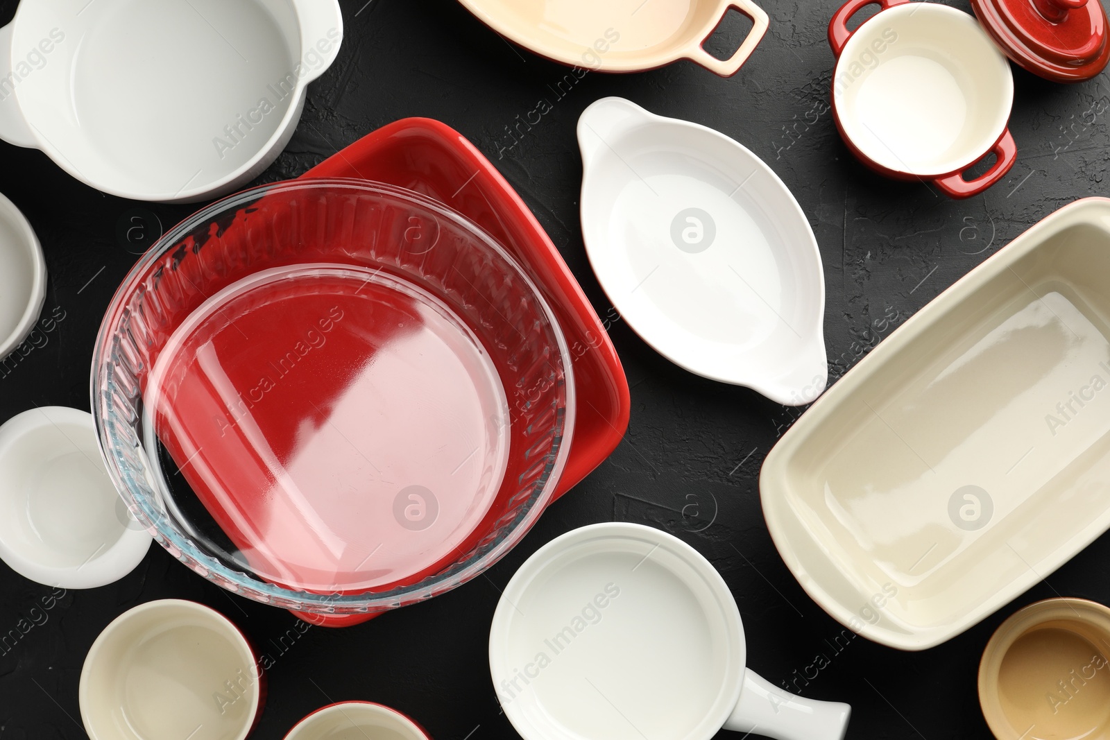 Photo of Many different casseroles on black table, flat lay