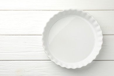 Photo of One ceramic casserole on white wooden table, top view. Space for text