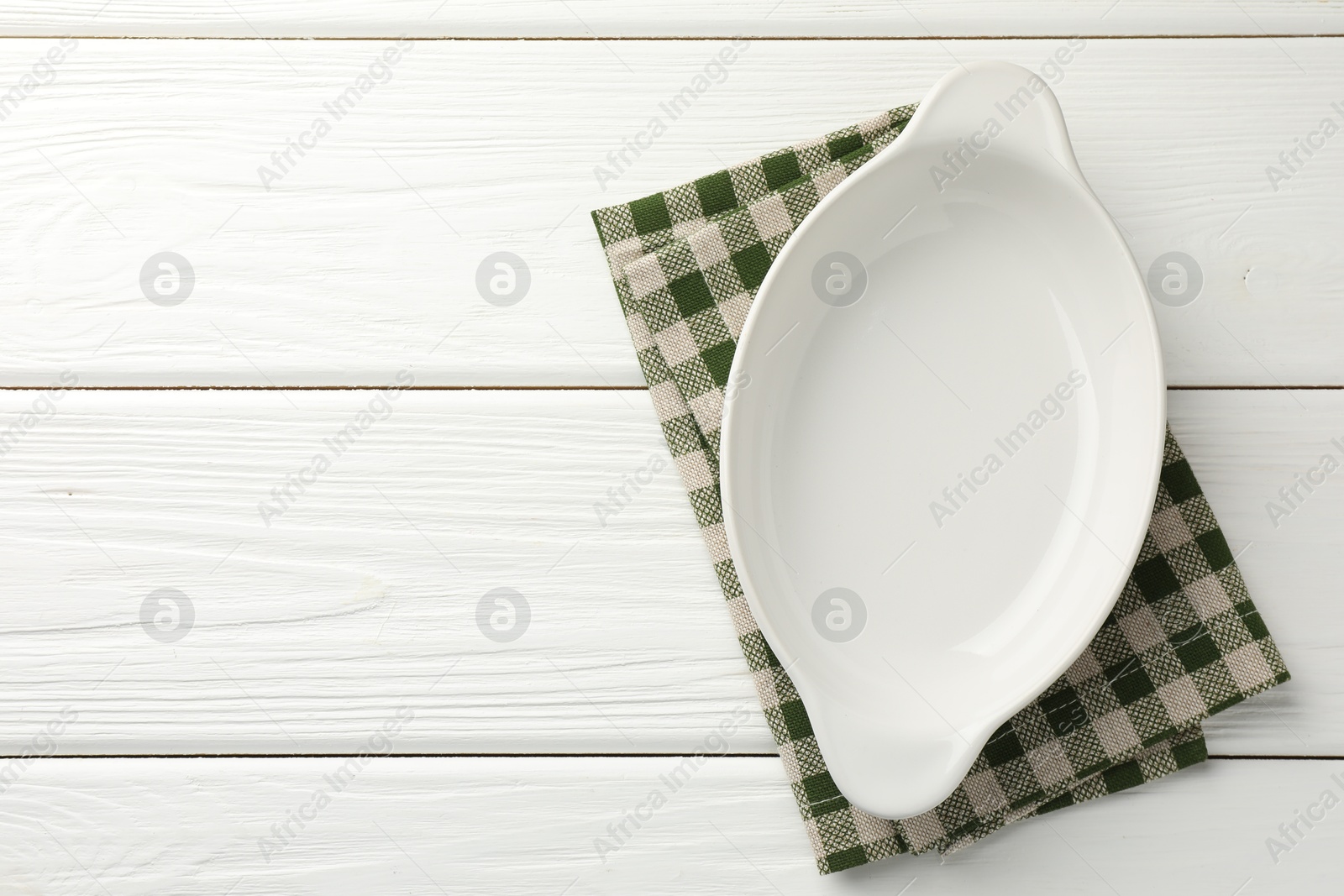 Photo of One ceramic casserole on white wooden table, top view. Space for text