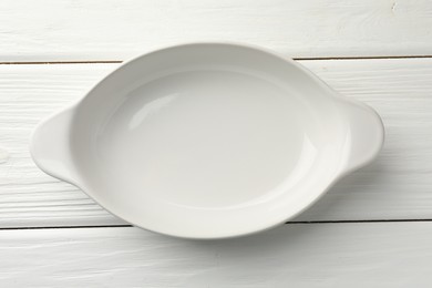 Photo of One ceramic casserole on white wooden table, top view