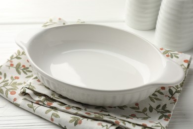 Photo of Ceramic casserole and shakers on white wooden table, closeup