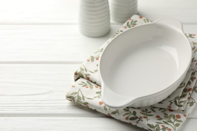 Photo of Ceramic casserole and shakers on white wooden table, closeup. Space for text