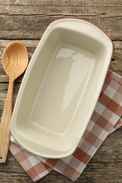 Photo of Ceramic casserole and spoon on wooden table, top view