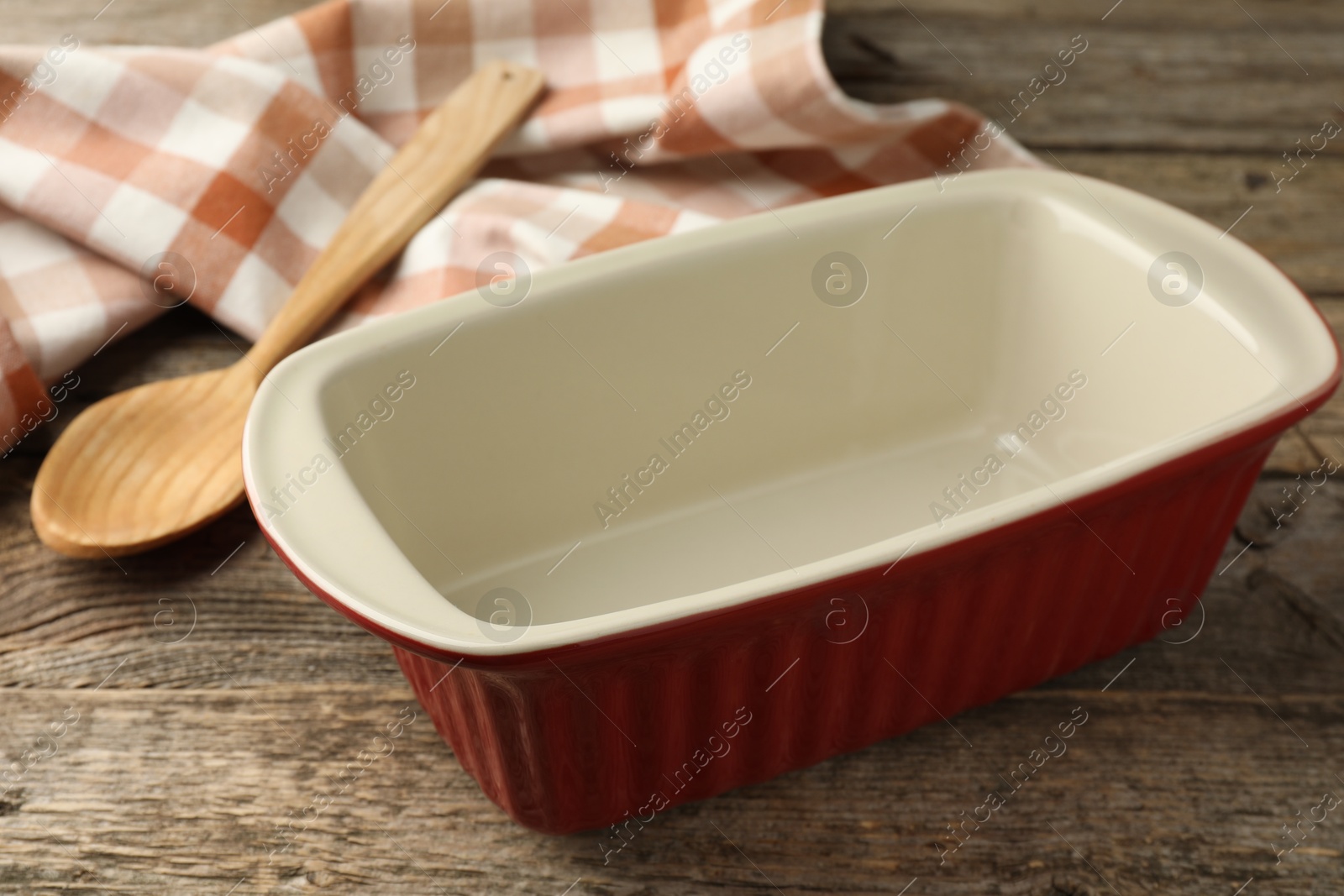 Photo of Ceramic casserole and spoon on wooden table, closeup