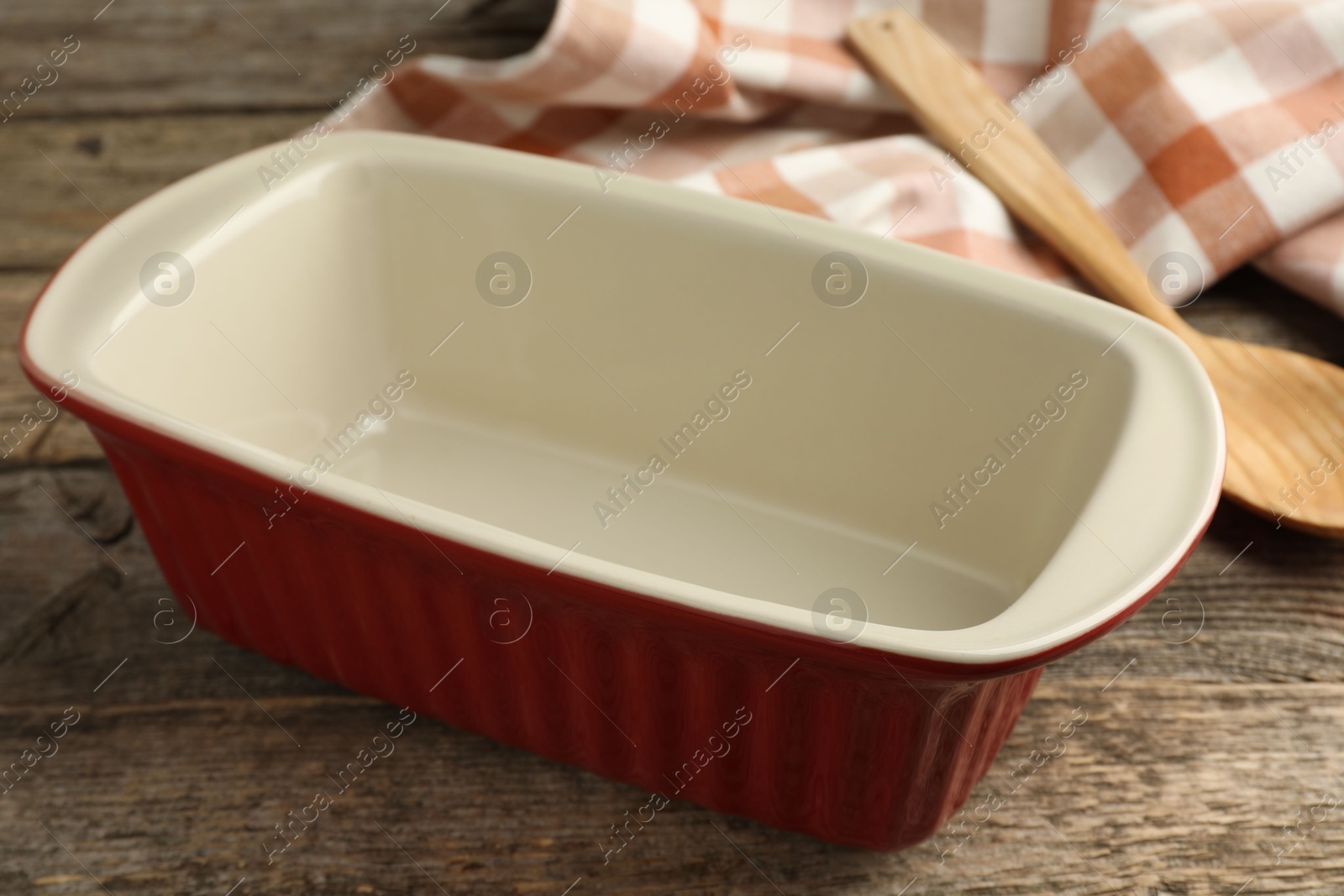 Photo of Ceramic casserole and spoon on wooden table, closeup