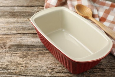 Photo of Ceramic casserole and spoon on wooden table, closeup. Space for text