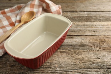 Photo of Ceramic casserole and spoon on wooden table, closeup. Space for text