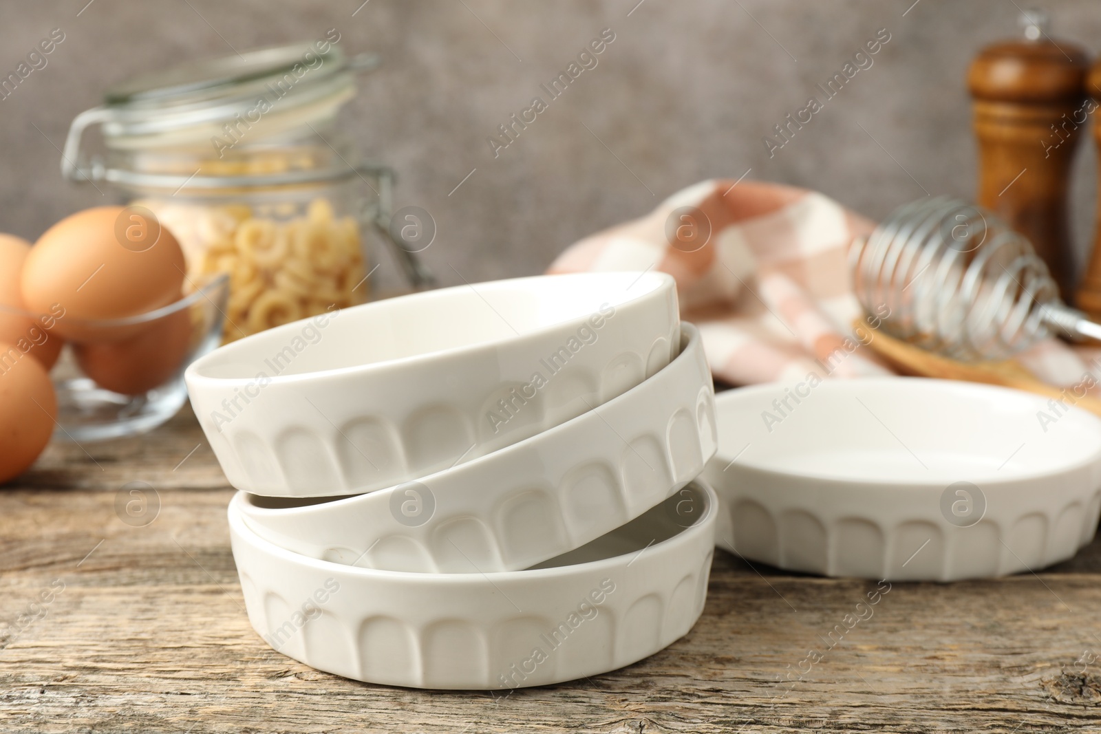 Photo of Many ceramic casseroles on wooden table, closeup