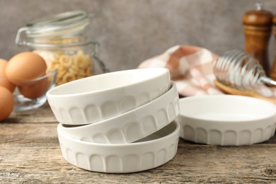 Photo of Many ceramic casseroles on wooden table, closeup