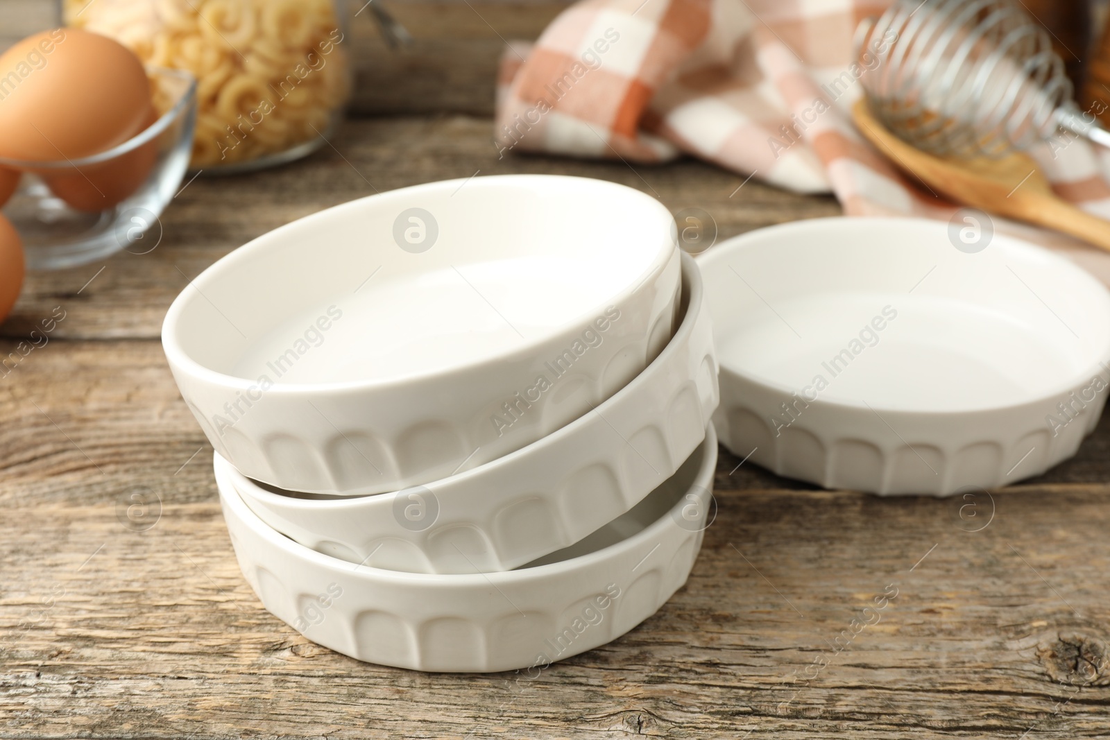 Photo of Many ceramic casseroles on wooden table, closeup