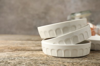 Photo of Ceramic casseroles on wooden table, closeup. Space for text