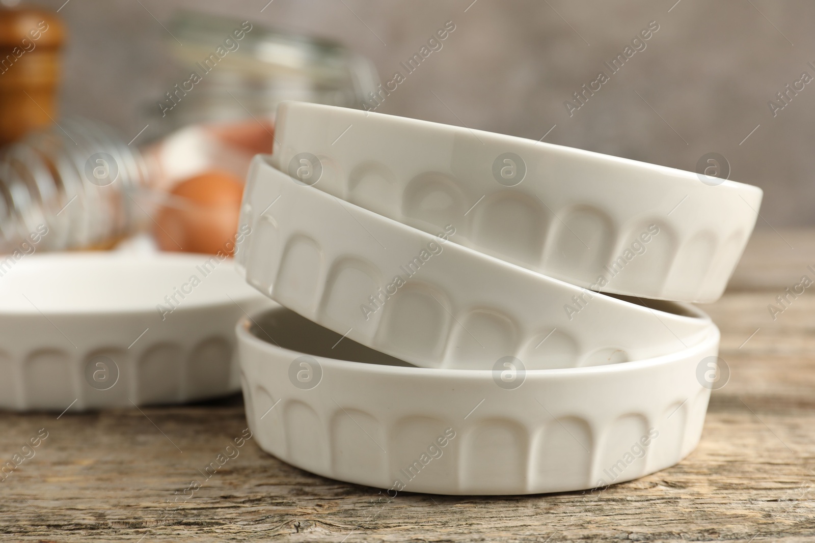 Photo of Ceramic casseroles on wooden table, closeup. Cooking utensil