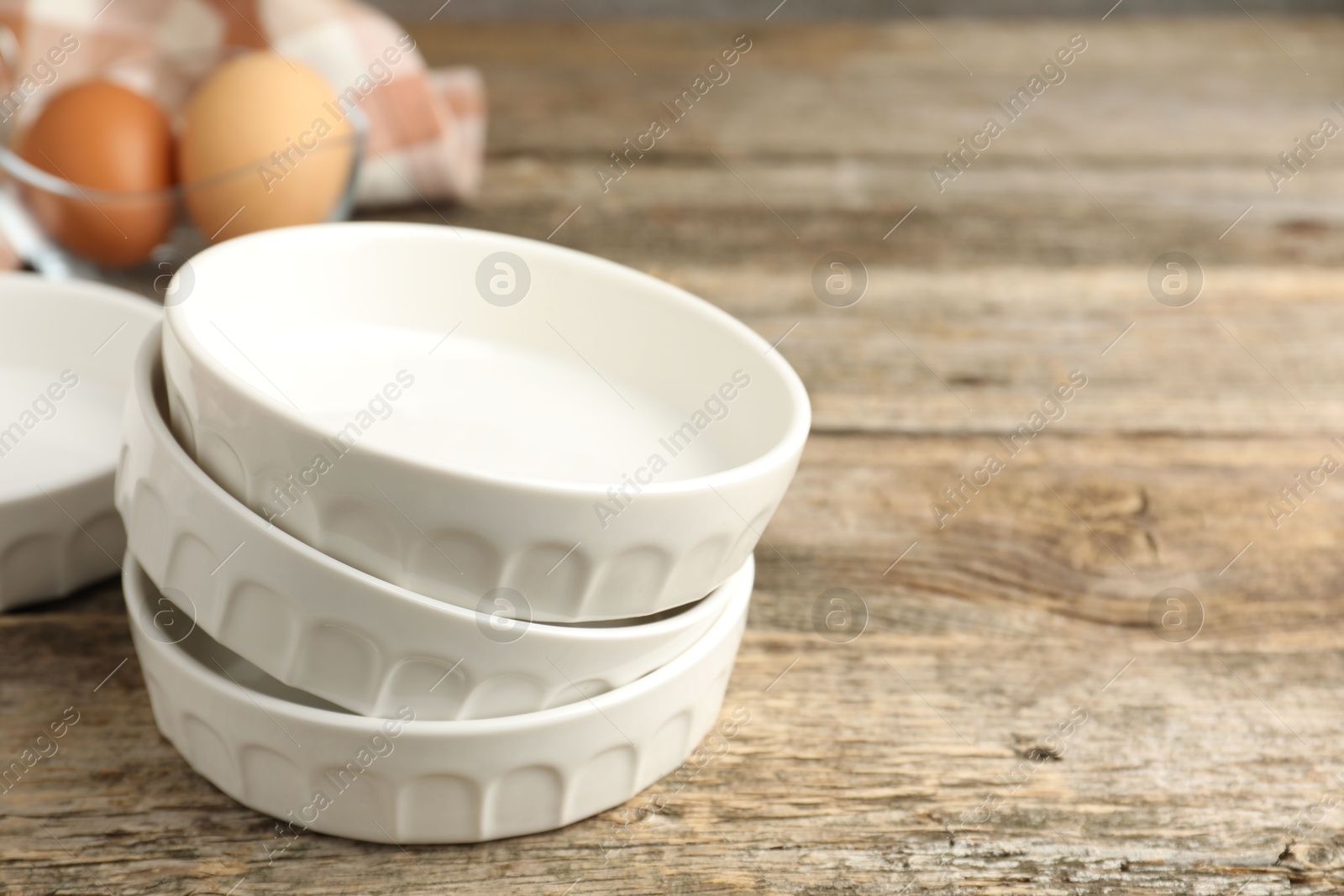 Photo of Ceramic casseroles on wooden table, closeup. Space for text