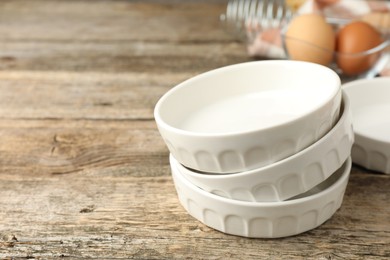 Photo of Ceramic casseroles on wooden table, closeup. Space for text