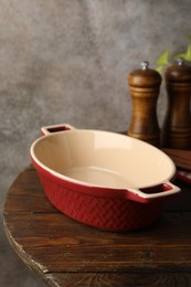 Photo of Ceramic casserole and shakers on wooden table, closeup