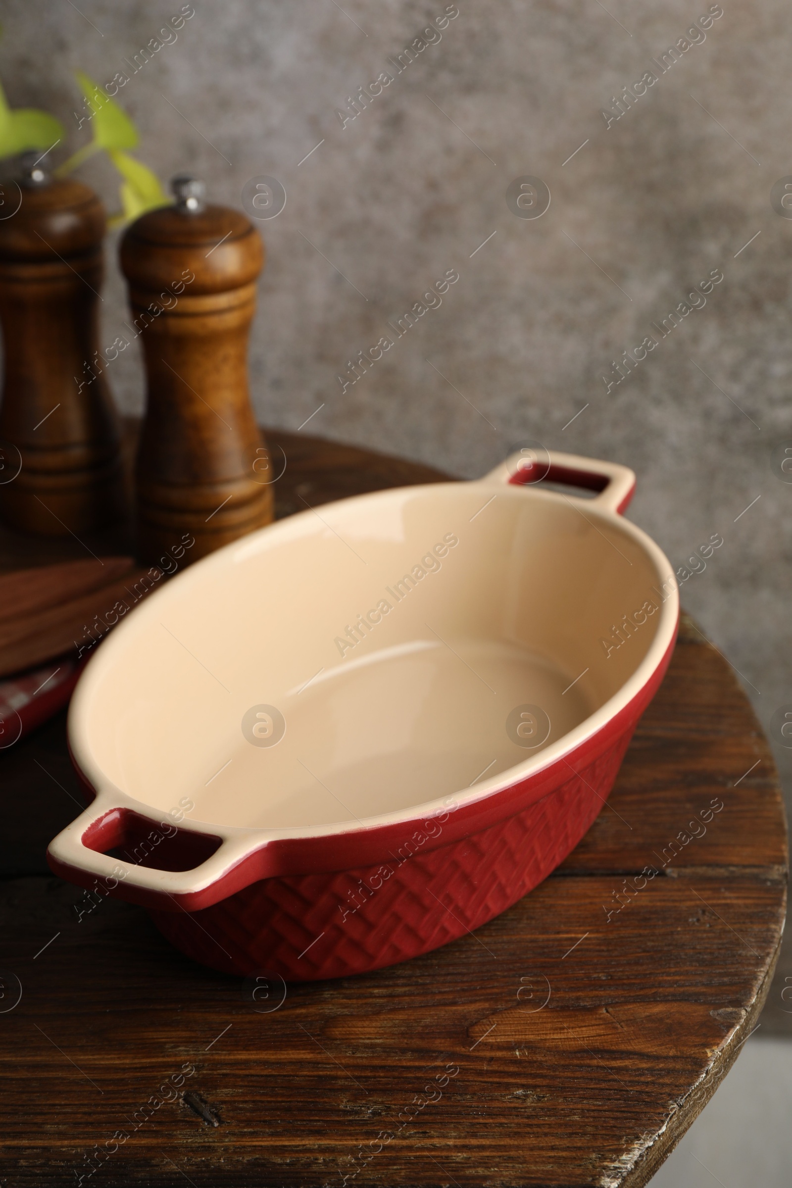 Photo of Ceramic casserole and shakers on wooden table, closeup