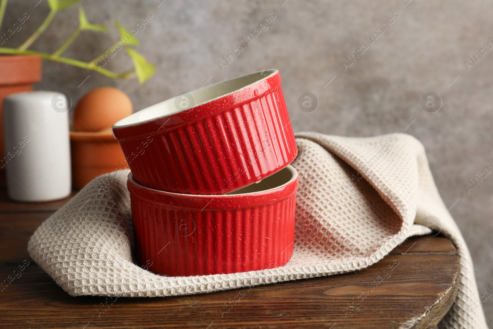 Photo of Red ceramic casseroles on wooden table. Cooking utensil