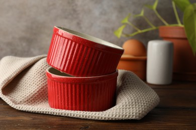 Photo of Red ceramic casseroles on wooden table. Cooking utensil