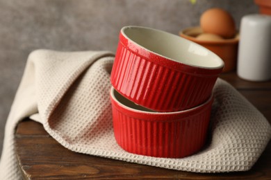 Photo of Red ceramic casseroles on wooden table, closeup