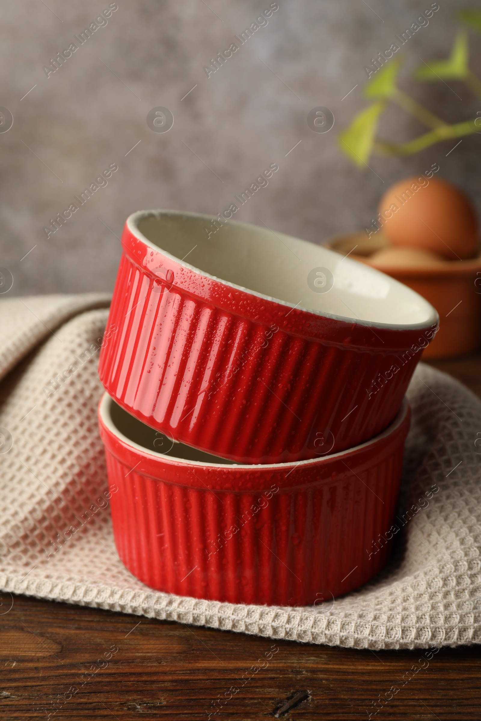 Photo of Red ceramic casseroles on wooden table, closeup