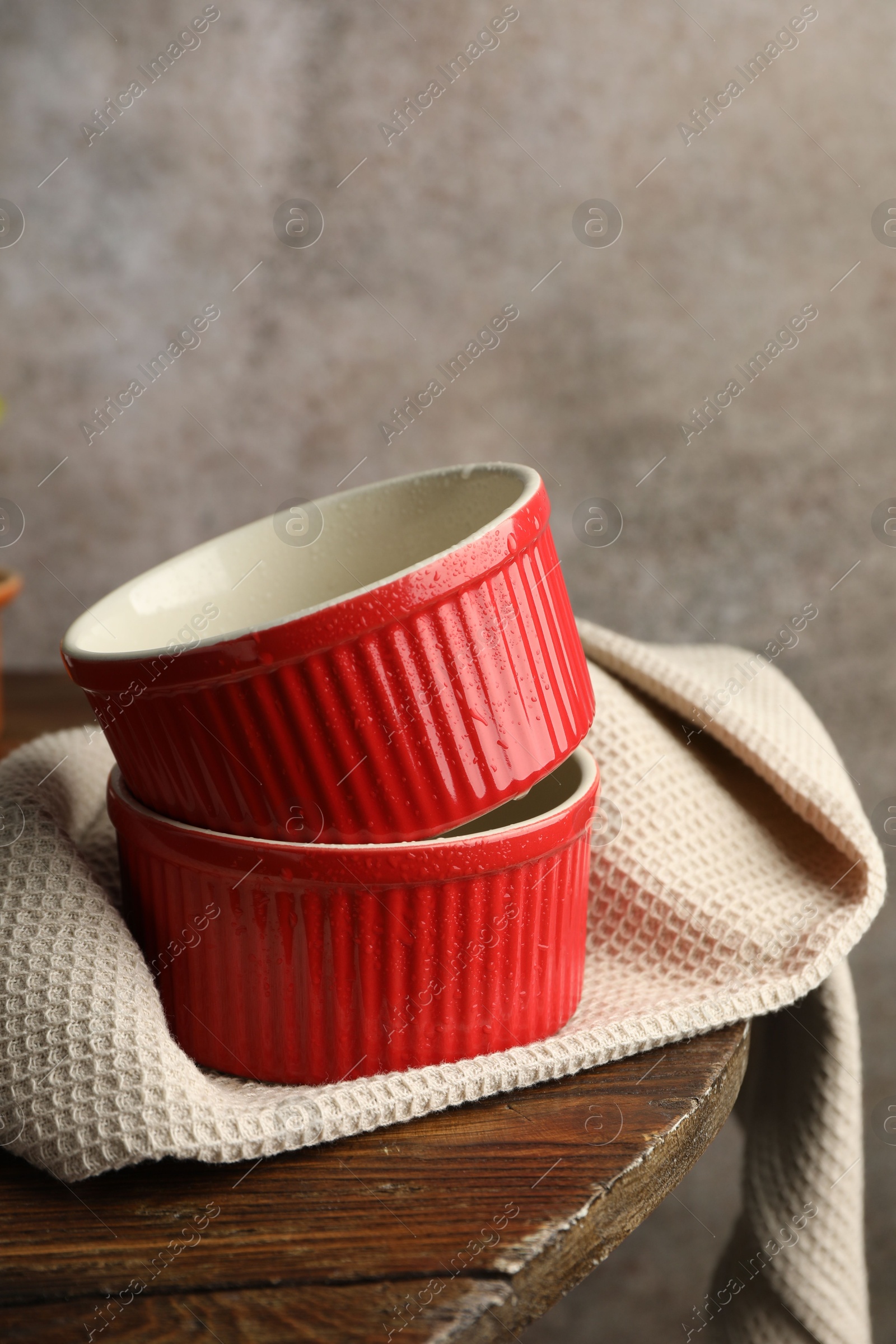 Photo of Red ceramic casseroles on wooden table. Cooking utensil