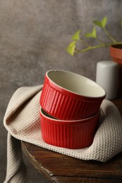 Photo of Red ceramic casseroles on wooden table. Cooking utensil