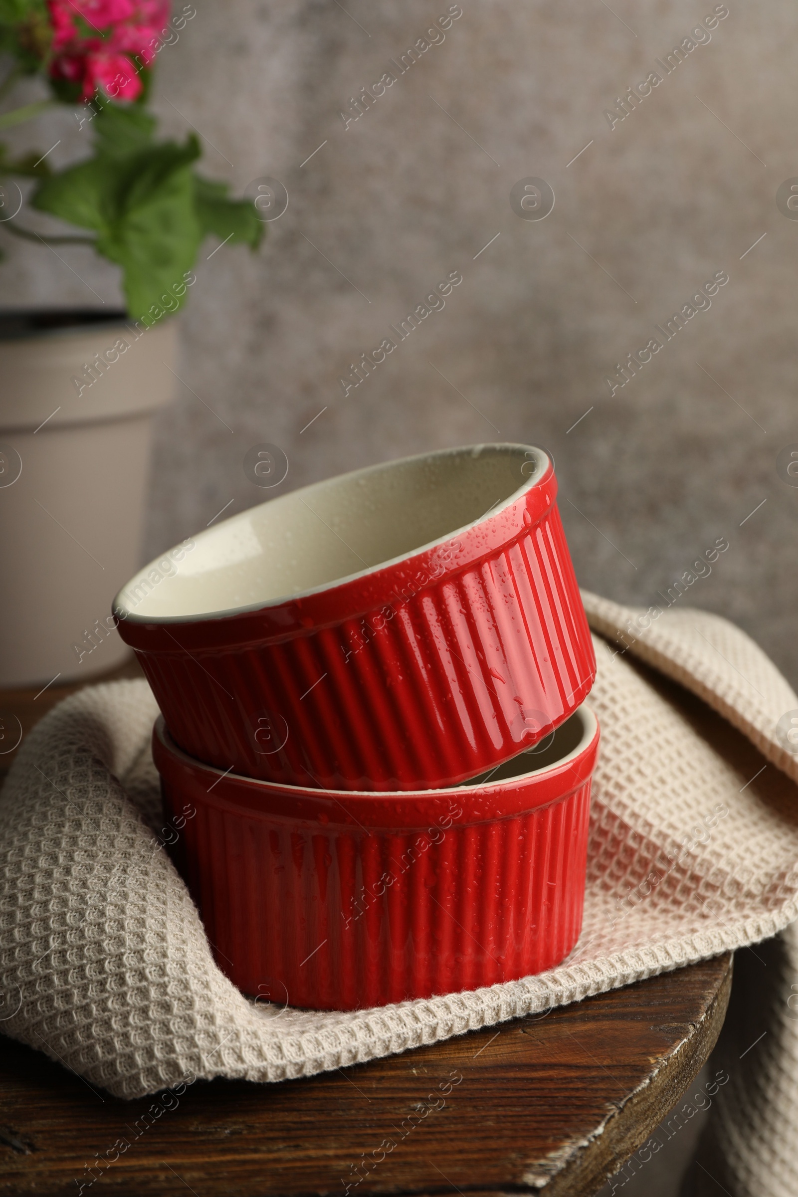 Photo of Red ceramic casseroles on wooden table. Cooking utensil