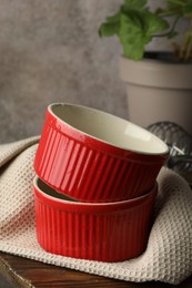 Photo of Red ceramic casseroles on wooden table, closeup