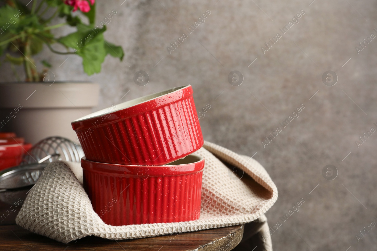 Photo of Red ceramic casseroles on wooden table, space for text