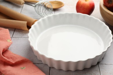 Photo of Ceramic casserole and other cooking utensils on light tiled table, closeup