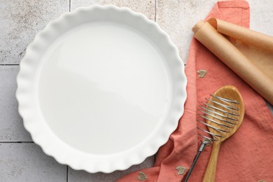 Photo of Ceramic casserole and other cooking utensils on tiled table, flat lay