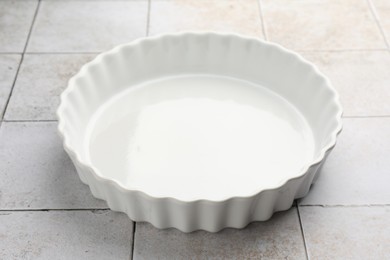 Photo of One ceramic casserole on light tiled table, closeup