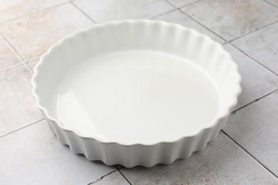 Photo of One ceramic casserole on light tiled table, closeup