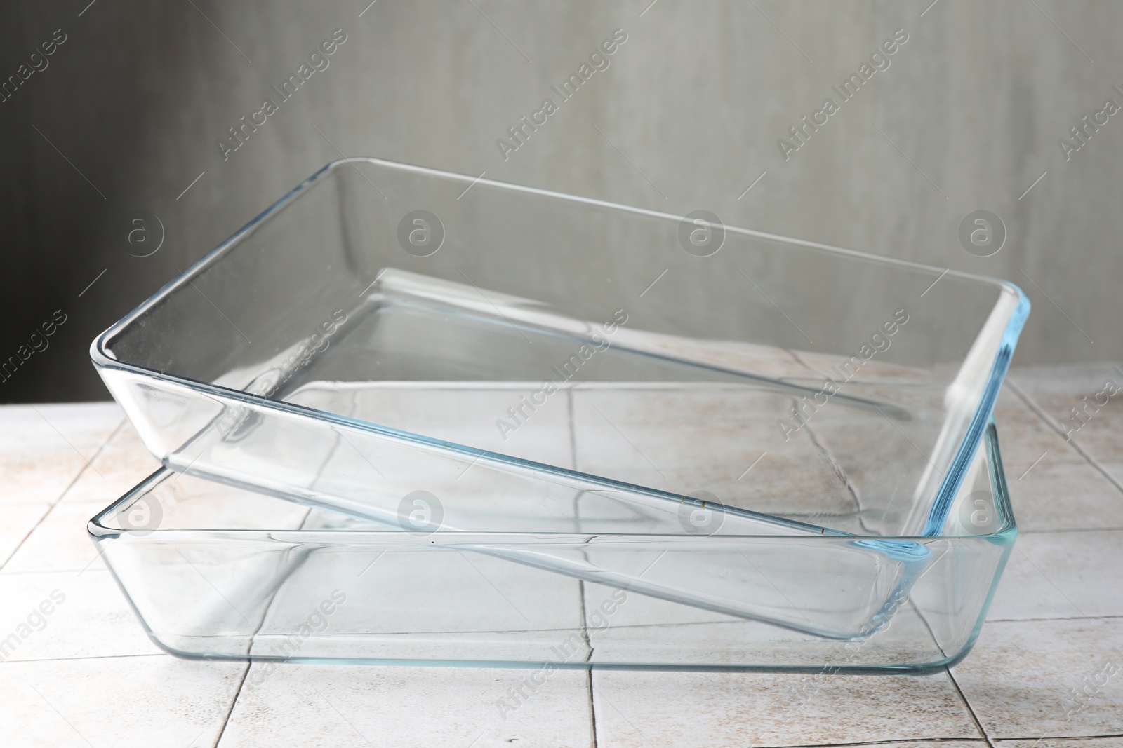 Photo of Glass casseroles on light tiled table, closeup