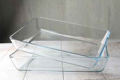 Photo of Glass casseroles on light tiled table, closeup