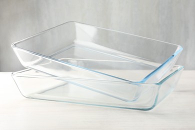 Photo of Glass casseroles on light wooden table, closeup