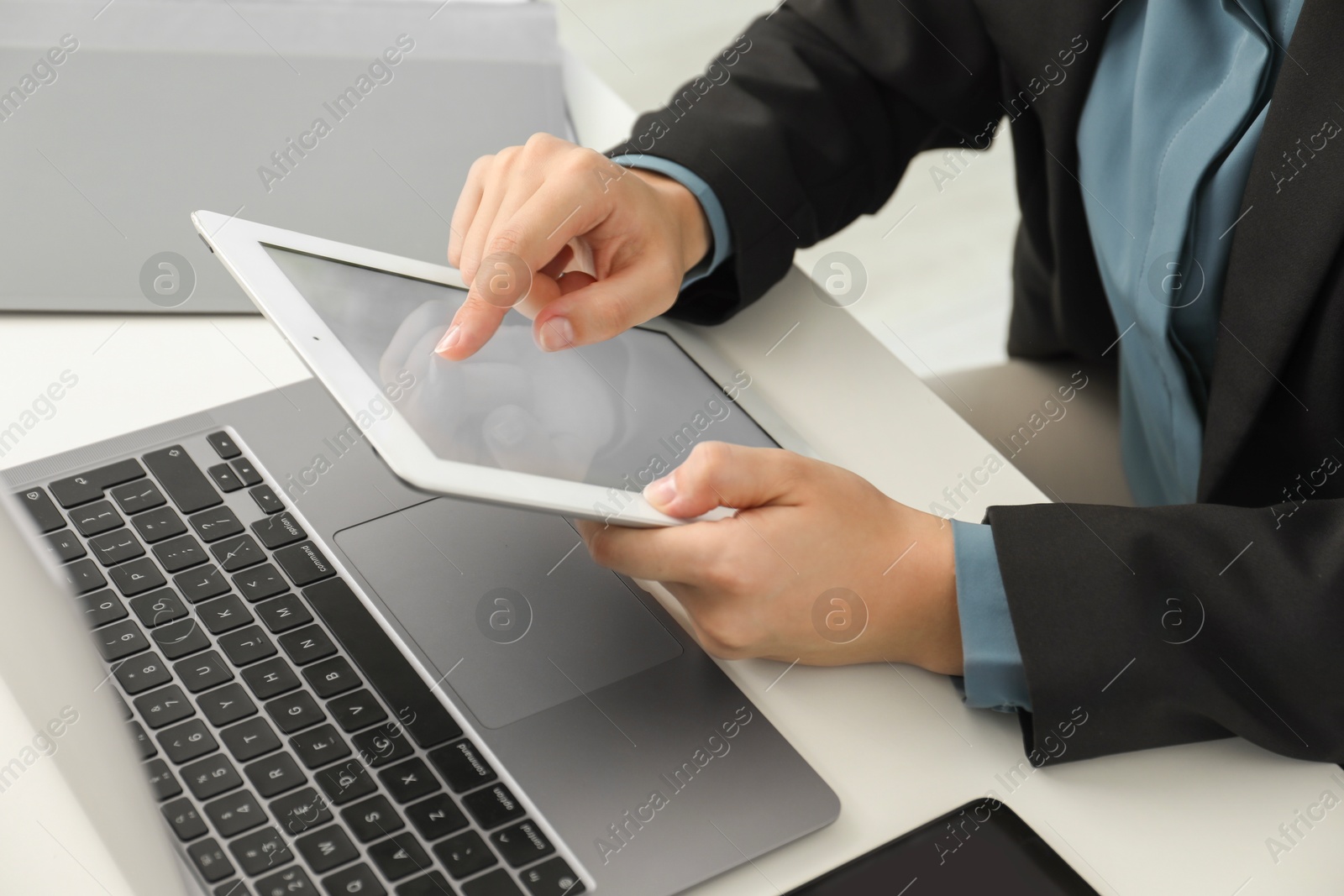 Photo of Businesswoman using tablet at white table indoors, closeup. Modern technology